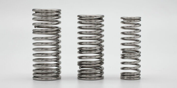Three industrial steel compression springs of different sizes on a white background