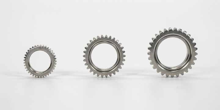 Three metal gear wheels of different sizes arranged on a white background