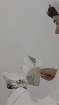 Close up of young man filling wall cracks with spackle