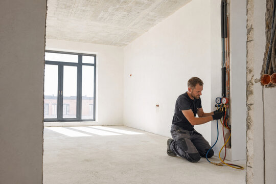 Un hombre trabaja en la instalaci&oacute;n de tuber&iacute;as en una habitaci&oacute;n en construcci&oacute;n durante el d&iacute;a