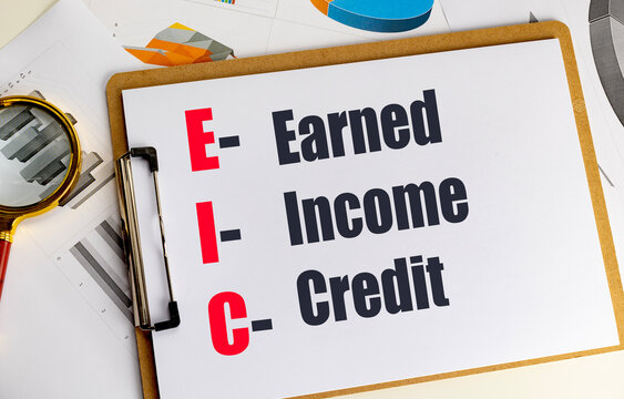 Earned income credit concept displayed on clipboard with financial charts and magnifying glass for tax analysis and accounting