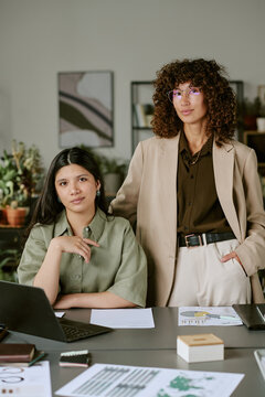 Portrait of diverse young adult businesswomen working in modern office, looking at camera. Image suitable for corporate communication and diversity in workplace marketing, vertical