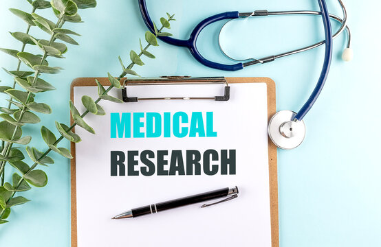 Medical research concept with clipboard, stethoscope, pen and green leaves on blue background, representing healthcare,