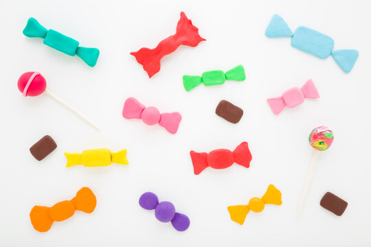 Created colorful candy shapes from modeling clay on light gray table background. Closeup. Little child handcraft. Flat lay. Top down view.