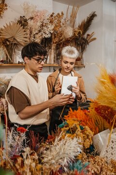 Two young florists discussing flower arrangements in a colorful flower shop