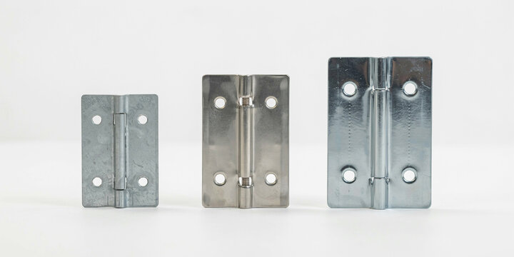 Three rectangular metal door hinges of different sizes on a white background