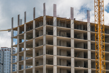Fototapeta premium Construction work on a high-rise building in an urban area with workers and machinery on a sunny day