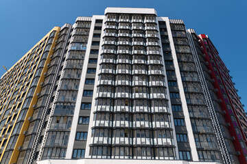 Fototapeta premium New apartment building with modern design showing multiple floors and balconies on a clear day in the city