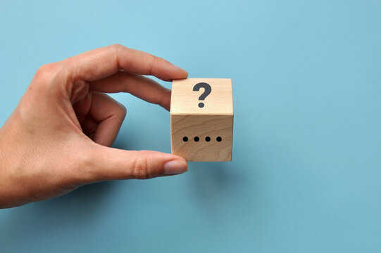 Question and Uncertainty Concept with Hand Holding a Wooden Cube