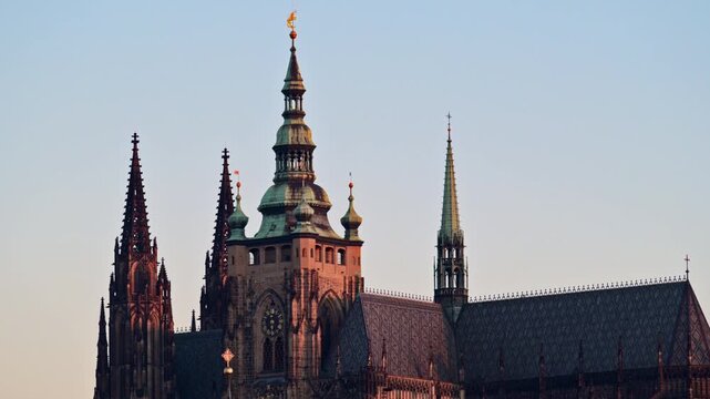 View of the Gothic spires and main tower of St. Vitus Cathedral in warm sunset light, Prague, Czech Republic.
