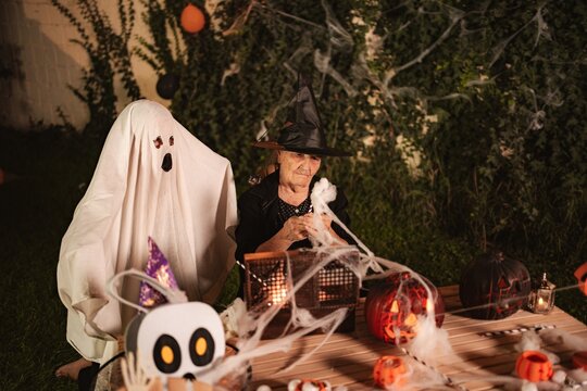 Mature adult woman and ghost celebrating Halloween with spooky decorations