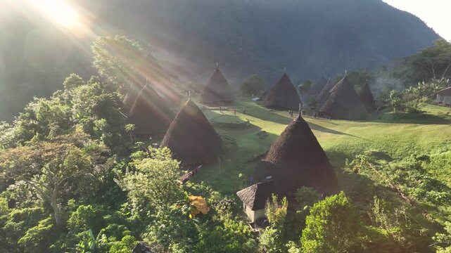 Aerial view of the traditional conical houses of Waerebo Village nestled in the lush green mountains of Satar Mese Barat, East Nusa Tenggara, Indonesia.