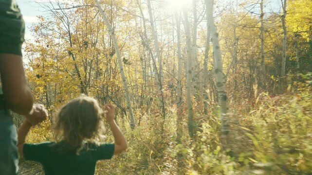 Family hiking along a boardwalk trail through a golden autumn forest