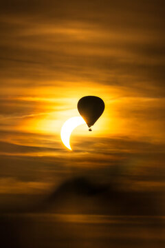 Ein Hei&szlig;luftballon vor einer partiellen Sonnenfinsternis
