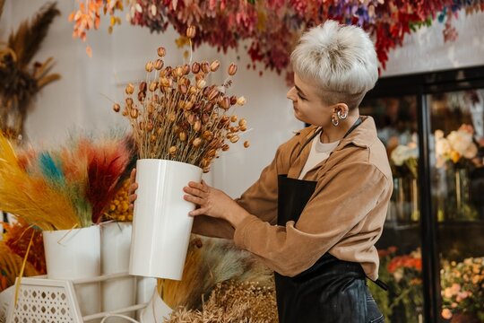 Young female florist holding fresh flowers in a colorful flower shop