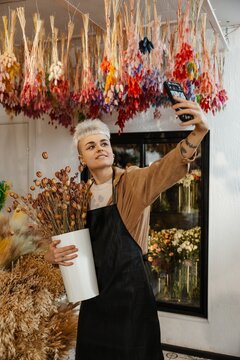 Young female florist taking a selfie in a colorful flower shop