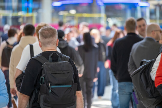 Backpack-wearing attendee moves through a dense convention crowd with other visitors blurred ahead.