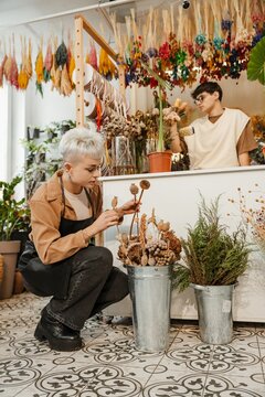 Two young florists arranging fresh flowers in a colorful flower shop