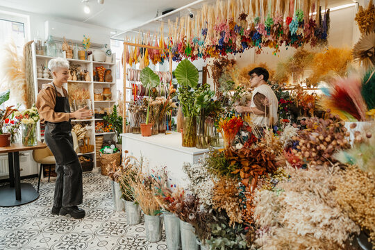 Two young florists arranging fresh flowers in a colorful flower shop