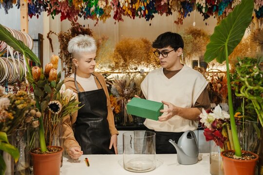 Two young florists holding a supply box in a colorful flower shop