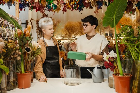 Two young florists arranging fresh flowers in a colorful flower shop