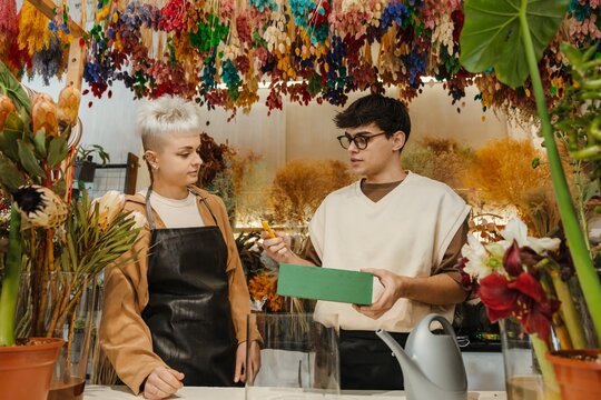 Two young florists showing a supply box in a colorful flower shop