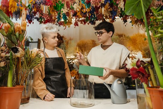 Two young florists discussing flower arrangements in a colorful flower shop