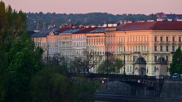 View of riverside facades above a stone bridge over the Vltava River at dawn, Prague, Czech Republic