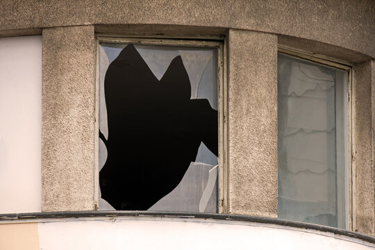 Window on building exterior with broken glass after public disorders 