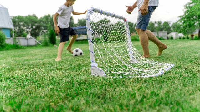 Two children play soccer on a grassy lawn