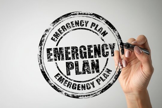 A hand draws an emergency plan circular stamp on transparent glass with a black marker. Use this graphic for business risk management and safety concepts.