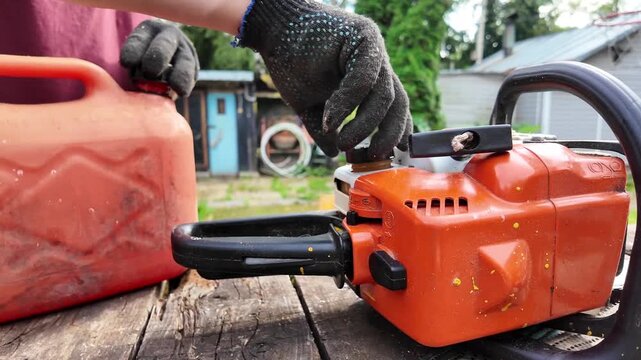Close view of hands preparing a chainsaw for operation, power tool maintenance, forestry equipment, professional service, outdoor workshop.