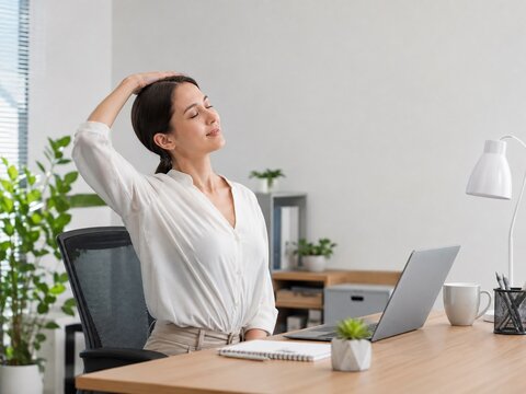 Asian office worker stretching neck at desk with laptop