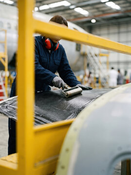 Factory worker apply composite material with roller