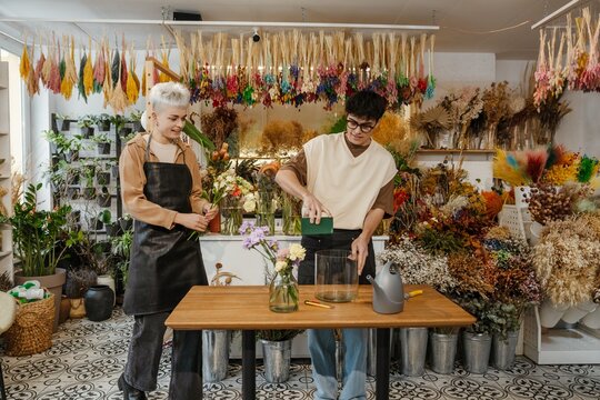 Two young florists arranging fresh flowers in a colorful flower shop