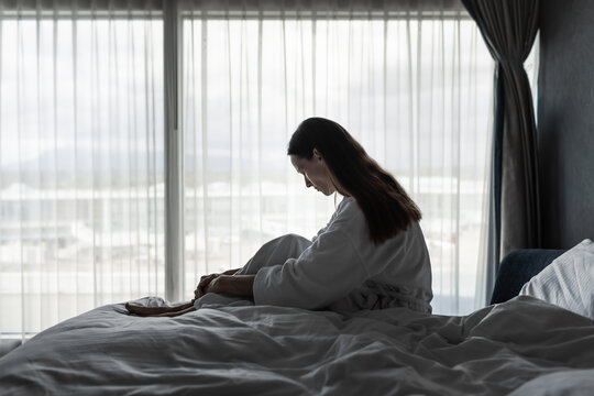 Stressed Woman Sitting Alone in Bed Feeling Overwhelmed, Anxious and Emotionally Exhausted
