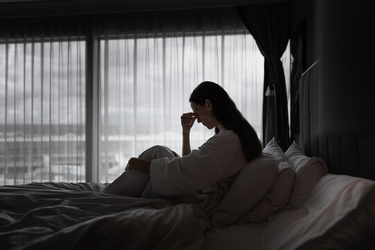 Stressed Woman Sitting Alone in Bed Feeling Overwhelmed, Anxious and Emotionally Exhausted
