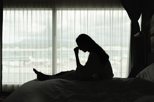 Sad Woman Sitting Alone in Bed Feeling Lonely and Emotionally Exhausted
