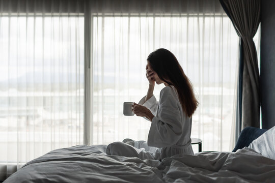 Stressed Woman Holding Coffee in Bed Feeling Overwhelmed and Emotionally Exhausted
