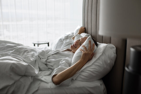 Happy Woman Waking Up Smiling and Feeling Refreshed in Comfortable Bed
