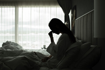 Naklejka na ściany i meble Stressed Woman Sitting in Bed with Head in Hand in the Morning 