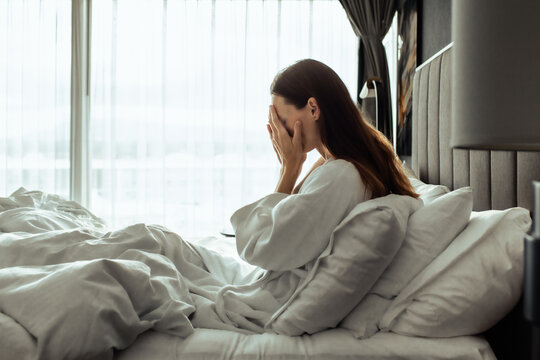 Tired Depressed Woman Covering Her Face While Sitting in Bed in the Morning
