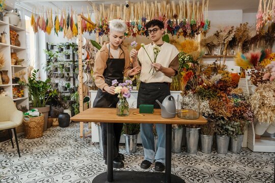 Two young florists arranging fresh flowers in a colorful flower shop