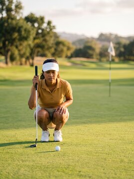 Golfer Observes Ball on Green at Golf Course During Late Afternoon