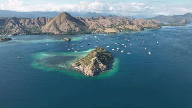 Aerial view of Pulau Kelor surrounded by turquoise waters and numerous boats in Komodo, East Nusa Tenggara, Indonesia.