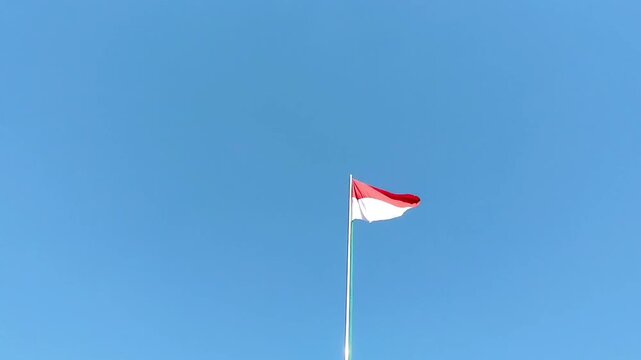 Indonesian Red and White Flag Waving in Wind Against Blue Sky Independence Day