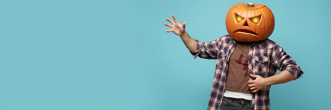 A person wearing a plaid shirt and a pumpkin head with glowing eyes stands against a light blue background, gesturing with one hand outstretched