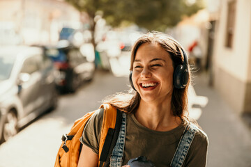 Young woman enjoying music and laughing on street