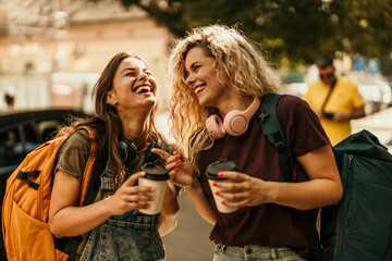 Happy young women friends laughing together traveling city