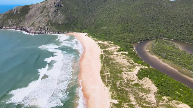 Drone View of Sinuous Freshwater River and Ocean Waves Crashing on Lagoinha do Leste Beach in Florianopolis Brazil, Pristine Coastal Dunes and Mountain Forest Coastline, Wild Travel Stock Video
